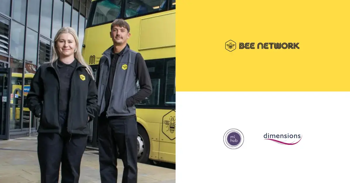 Two people stood in front of a yellow bus. 
