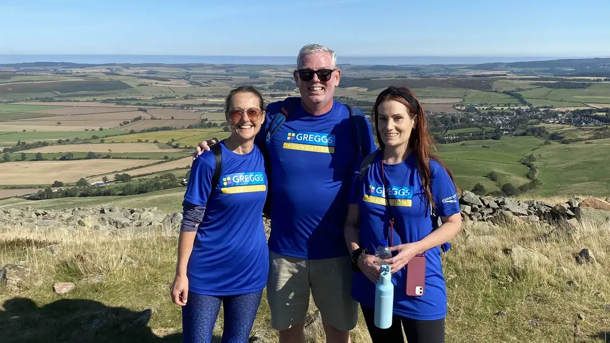 Three people stood on a hillside. 