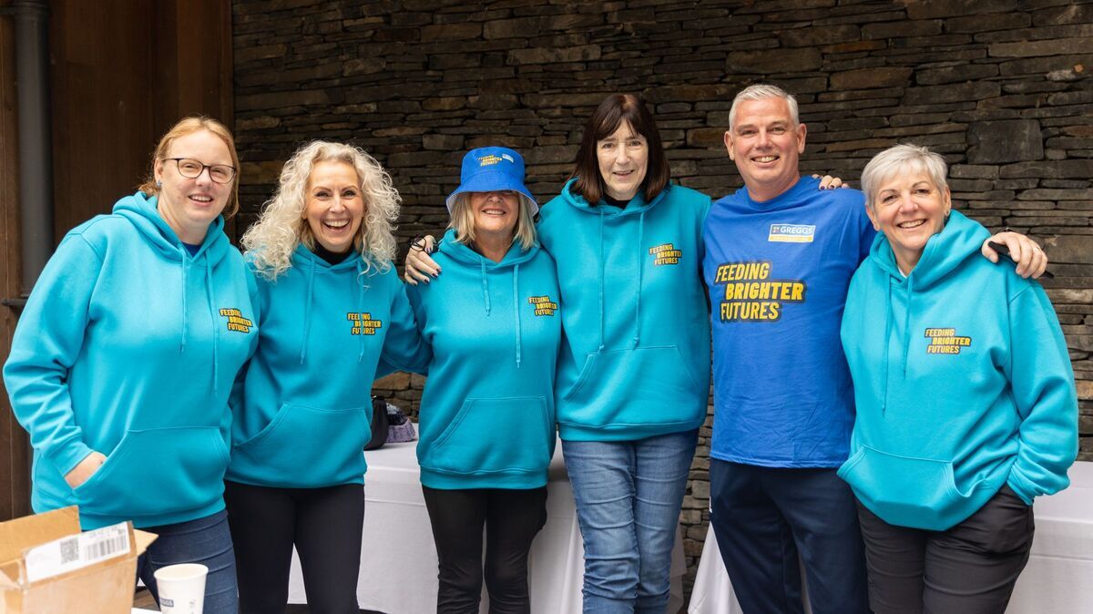A group of people stood together wearing event branded blue sweatshirts. 