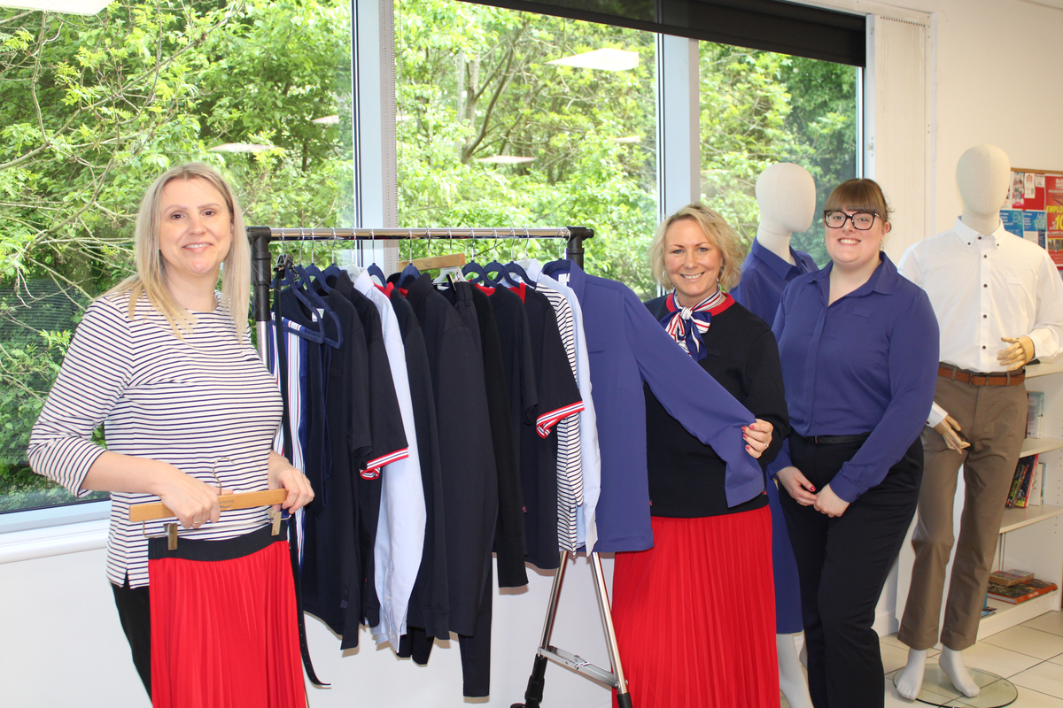 3 people stood in front of a rail of clothing items