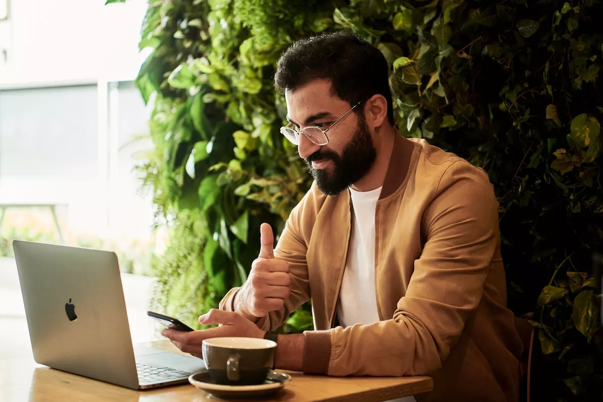 A man sat working at a laptop with a coffee