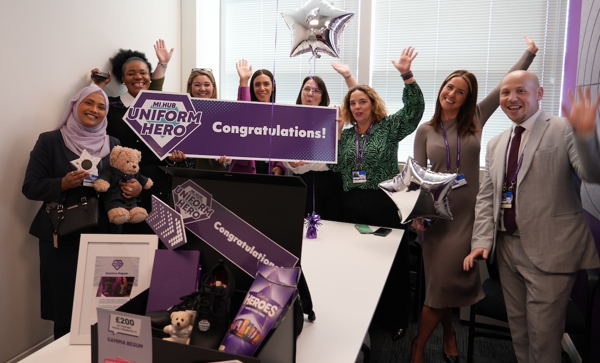 A group of people stood around a box of prizes holding up a banner